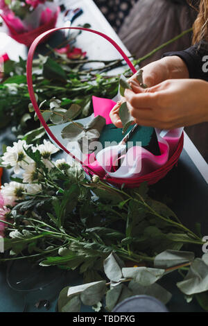 Master class di fiorista femminile al lavoro con il mazzo di fiori. Ragazza rendendo bouquet di vari fiori d'autunno. Business donna fioraio al negozio di fiori Foto Stock