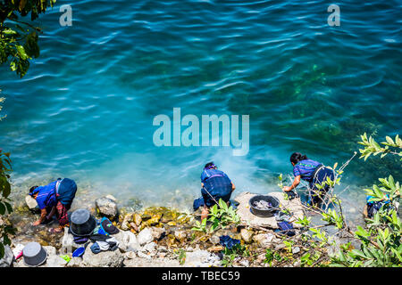 San Antonio Palopo, lago Atitlan, Guatemala - Marzo 20, 2019: Maya indigeni ladies lavare la biancheria a Lakeside, altipiano guatemalteco. Foto Stock