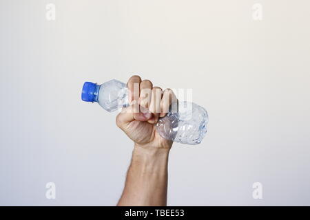 Spremitura a mano la bottiglia di plastica che rappresentano il movimento contro l'inquinamento e per il riciclaggio. Foto Stock