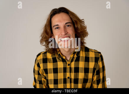 Ritratto di spensierata teen maschio con capelli lunghi in camicia casual guardando fiduciosi e sicuri di sé. Sorridente e fissando la fotocamera. Studio shot. In natur Foto Stock