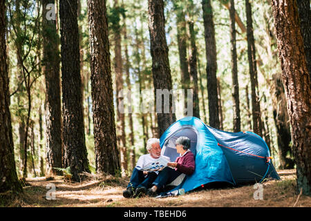 La gente attiva vecchia età caucasian coppia senior travel con tenda da campeggio - sedersi nella foresta per divertirsi insieme - rapporto per sempre concetto fo Foto Stock