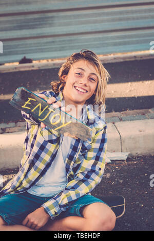 Felice allegro bel giovane adolescente con informali hipster vestiti mostra lavoro motivazionale godere scritto su legno - bello stile di vita di persone e modern boy Foto Stock