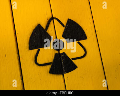 Segno di radioattività, close-up. Segno di radiazioni su un giallo tagliere in legno. Segno radioattivi - il simbolo di radiazione. Giallo e nero pericolo radioattivo, Foto Stock