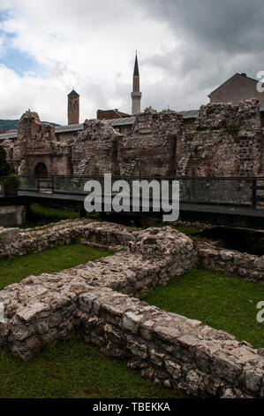 Bosnia: Sarajevo la Torre dell Orologio e il minareto di Gazi Husrev-beg Mosque visto da resti di Taslihan, una pietra 1540 inn e caravanserai Foto Stock