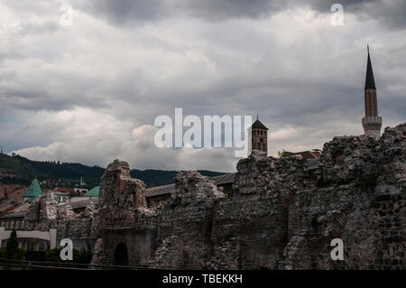 Bosnia: Sarajevo la Torre dell Orologio e il minareto di Gazi Husrev-beg Mosque visto da resti di Taslihan, una pietra 1540 inn e caravanserai Foto Stock