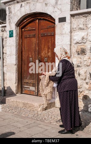 Sarajevo: anziani donna bosniaca vendere ricamati a mano con tovaglie e centrini in Bascarsija square, il vecchio bazar e il centro storico della città Foto Stock