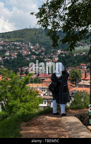 Sarajevo, Bosnia: donna velata guardando lo skyline della città con Alpi Dinariche e fiume Miljacka dalla sommità di Zuta Tabija (giallo Fortezza) Foto Stock