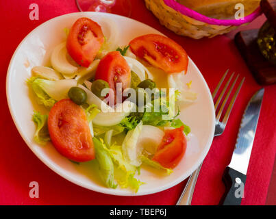 Valenciana tradizionale insalata con foglie di lattuga, ​​tomatoes a fette, la cipolla e le olive con olio di oliva Foto Stock