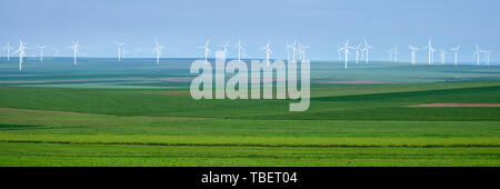 Panorama di bianco le turbine eoliche su strati di colture agricole con varie sfumature di verde, su un cielo nuvoloso, in Dobrogea, Romania. Concetto per susta Foto Stock