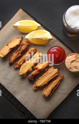 Raffreddamento per rack con profondo fritto baby pannocchie di granoturco, salse e bicchiere di birra sul tavolo Foto Stock