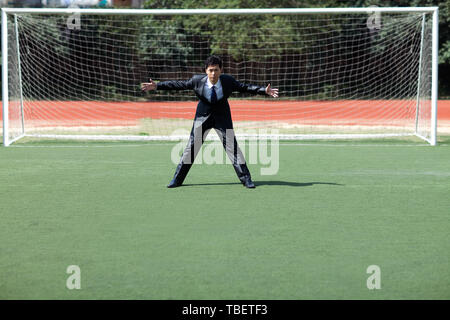 La gente di affari giocando a calcio su un campo di calcio Foto Stock