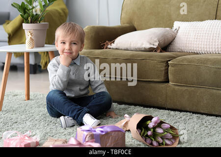 Little Boy con doni e fiori per la sua madre a casa. 8 marzo Celebrazione Foto Stock
