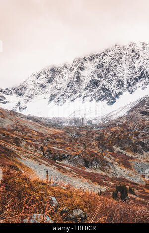 Redhaired montagna. Erba gialla in Valle d'autunno. Rocce sotto la neve su orizzonte. Foto Stock