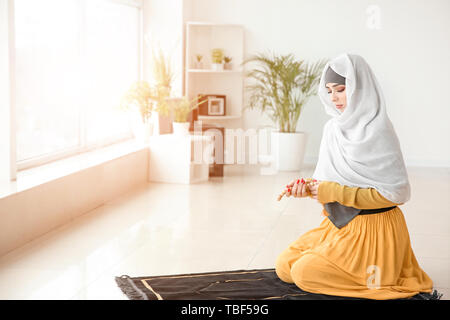 Giovane donna musulmana pregando in casa Foto Stock