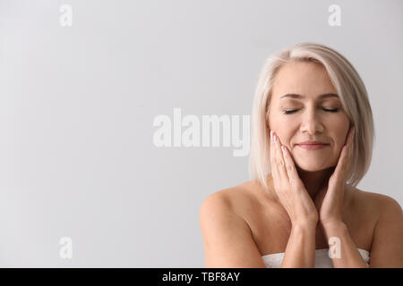 Donna matura donazione massaggio viso su sfondo chiaro Foto Stock