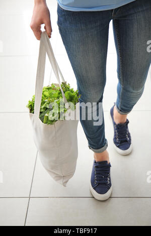 Giovane donna con verdure fresche in sacchetto di eco in ambienti interni Foto Stock