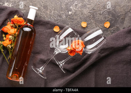 Bottiglia di vino, bicchieri e fiori su sfondo grunge Foto Stock