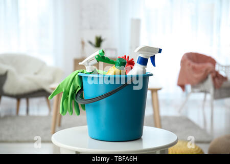 Benna con materiali per la pulizia sul tavolo a casa Foto Stock