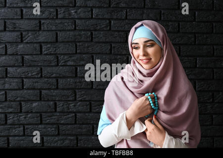 Donna musulmana con tasbih su sfondo scuro Foto Stock