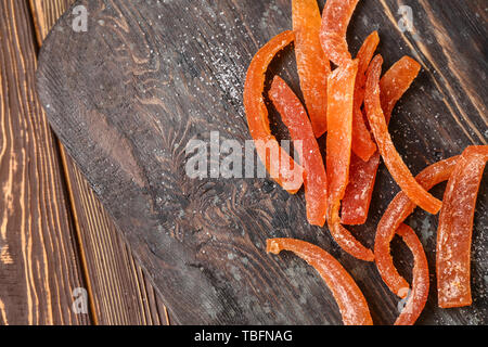 Gustosa arancia candita pela sulla tavola di legno, primo piano Foto Stock