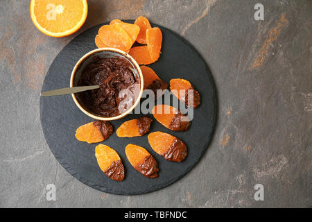 Piastra di ardesia con gustosi ricoperta di cioccolato mango sul tavolo scuro Foto Stock