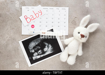 Immagine Sonogram, test di gravidanza, calendario e toy su sfondo grigio Foto Stock