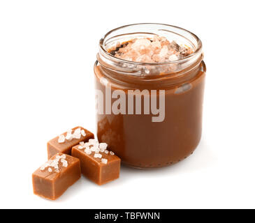 Vasetto di gustosi piatti salati con caramello caramelle su sfondo bianco Foto Stock