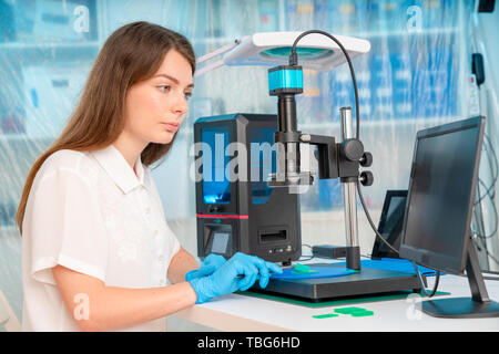 Lavoratore di sesso femminile nel controllo di resina LCD / DLP / SLA stampante 3D nel laboratorio di tecnologia Foto Stock