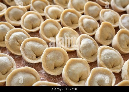 In casa gnocchi di russo, pelmeni, coperto di farina a fontana sul tagliere in legno Foto Stock