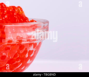 Caviale rosso in una ciotola di vetro su bianco Foto Stock