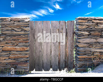 Natura paesaggio estivo. Vista sulla campagna e rustico cancello in stalattite muro nel villaggio Cadaces, Spagna Foto Stock