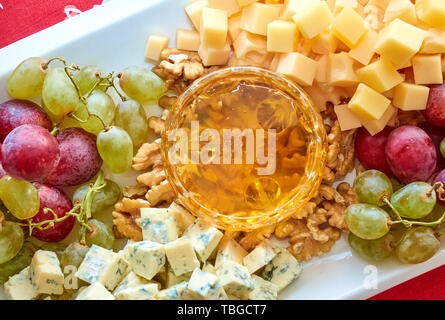 Diversi tipi di formaggio, l'uva, le noci e il miele gourment assortiti, angolo superiore Foto Stock