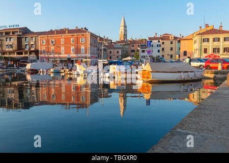 Izola, Slovenia - 1 Maggio 2019: panoramica del porto con barche e case vivacemente colorate sul lungomare al tramonto in Izola - Isola. Foto Stock