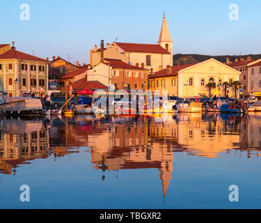 Izola, Slovenia - 1 Maggio 2019: panoramica del porto con barche e case vivacemente colorate sul lungomare al tramonto in Izola - Isola. Foto Stock