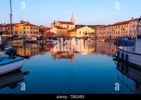 Izola, Slovenia - 1 Maggio 2019: panoramica del porto con barche e case vivacemente colorate sul lungomare al tramonto in Izola - Isola. Foto Stock