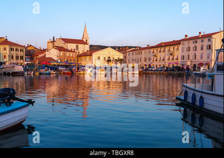 Izola, Slovenia - 1 Maggio 2019: panoramica del porto con barche e case vivacemente colorate sul lungomare al tramonto in Izola - Isola. Foto Stock