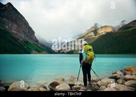 Una femmina di escursionista presso il Lago Louise in Banff National Park con le montagne e le foreste in Canada. Foto Stock