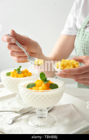 Donna decorazione di gustoso panna cotta a tavola Foto Stock