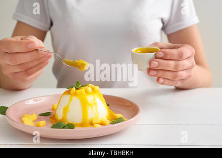 Donna decorazione di gustoso panna cotta a tavola Foto Stock