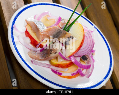 Patate fritte con fette di dolce-cured aringa e cipolle servito sulla piastra Foto Stock