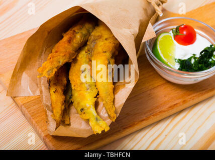 Pesce - patatine fritti in pastella di acciughe con la classica salsa di formaggio cremosa e verdi Foto Stock