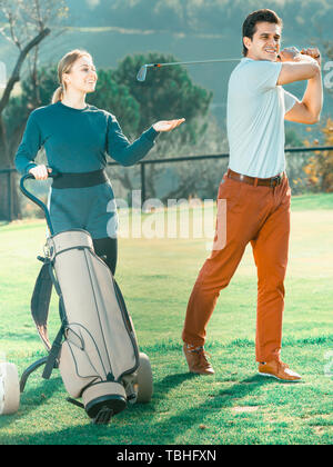 Giovane ragazza guardando il gioco maschio di giocatore di golf su un campo da golf Foto Stock