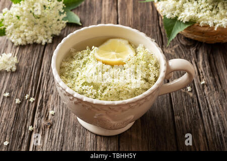 Macerazione di freschi fiori di sambuco e limone in acqua per preparare in casa lo sciroppo a base di erbe Foto Stock