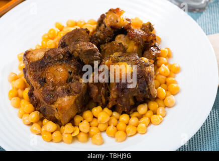 Brasati oxtails con ceci su una piastra bianca Foto Stock