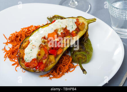 Deliziosi melanzane al forno ripiene con mix di verdure servito con salsa tzatziki Foto Stock