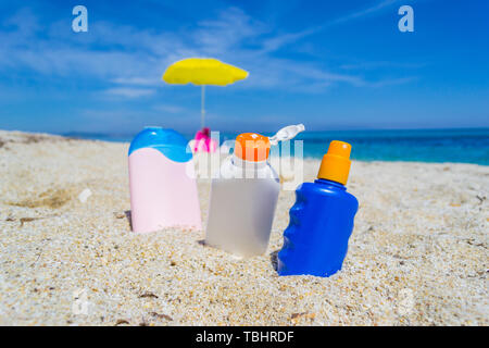 Lozione solare bottiglie sulla sabbia in Sardegna, Italia Foto Stock