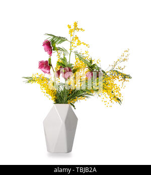 Bouquet con bellissimi fiori di mimosa in vaso su sfondo bianco Foto Stock