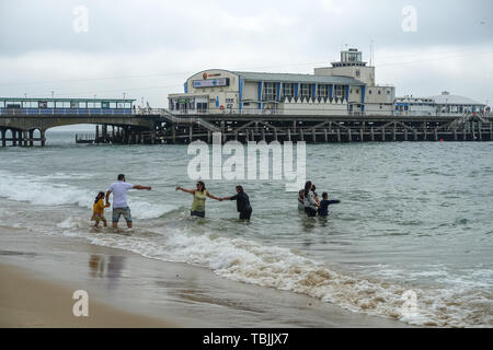 Bournemouth Dorset, Regno Unito, 2 giugno 2019. Un fantastico inizio nel sud dell'Inghilterra ha fatto sì che alcuni visitatori per la spiaggia erano ben avvolti in cappotti e felpe con cappuccio. Questa famiglia prese il mare completamente vestito. La previsione è stata per 29 gradi Celsius ma ha soltanto raggiunto 20 gradi a metà mattina con un fresco vento. Credito: Mick Flynn/Alamy Live News Foto Stock