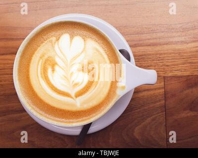 Foto aerea di un preparato di fresco Cappuccino con una bella decorazione in cima sat sulla sommità di uno sfondo di legno Foto Stock
