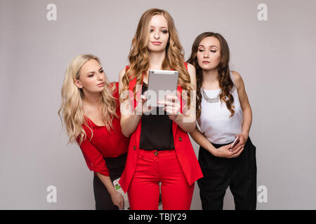 Tre signore usando i gadget. Tre bellissime elegante delle giovani donne in vestiti casual Foto Stock